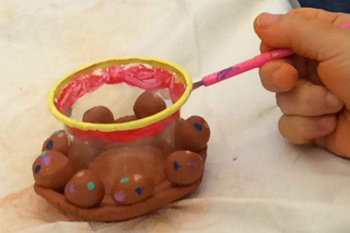 Hand reaching into the scene to light a small clay lantern